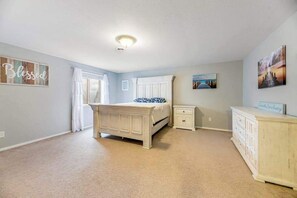 Ein Schlafzimmer mit Bett, Nachttisch, Schminktisch und Kunstwerken an den Wänden.