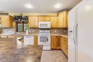 A kitchen with wooden cabinets, a microwave, a stove, and a refrigerator.
