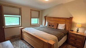 A bedroom with a wooden bed, two bedside tables, a nightstand, a desk, and a patterned rug. - Legacy Lodge- 4BR Lodge Minutes from Deadwood (Sturgis)