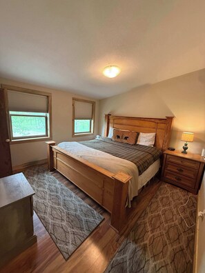 A bedroom with a wooden bed, two bedside tables, a nightstand, a desk, and a patterned rug. - Legacy Lodge- 4BR Lodge Minutes from Deadwood (Sturgis)