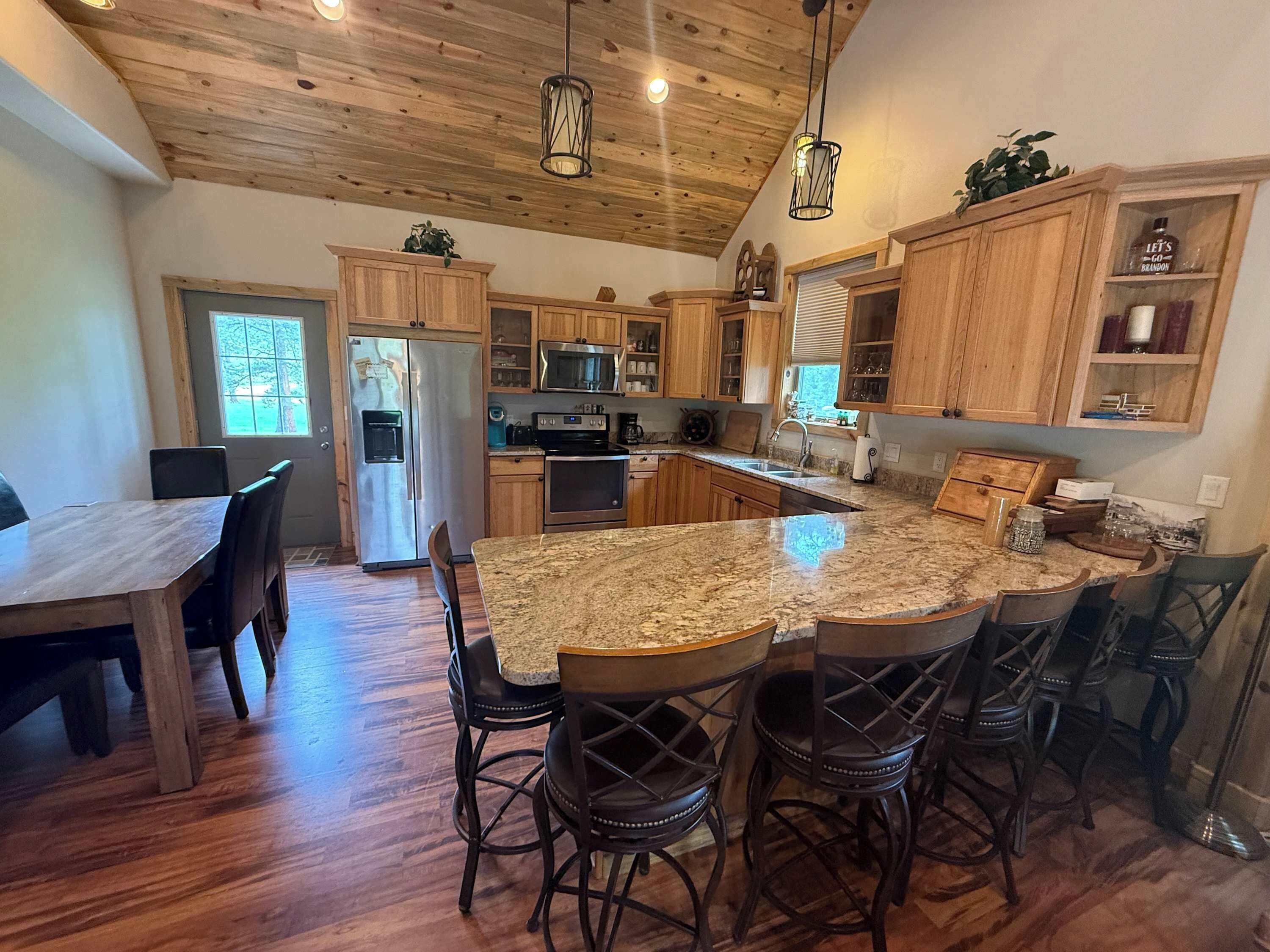 A spacious kitchen with wooden cabinets, a granite countertop, and a dining area with chairs.