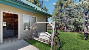 A house with a porch, a swing, and a view of the surrounding trees. - Legacy Lodge - 4BR Lodge Minutes from Deadwood (Sturgis)
