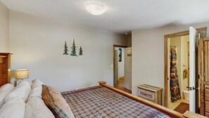 Un dormitorio con cama, mesita de noche, espejo y puerta que da al baño.