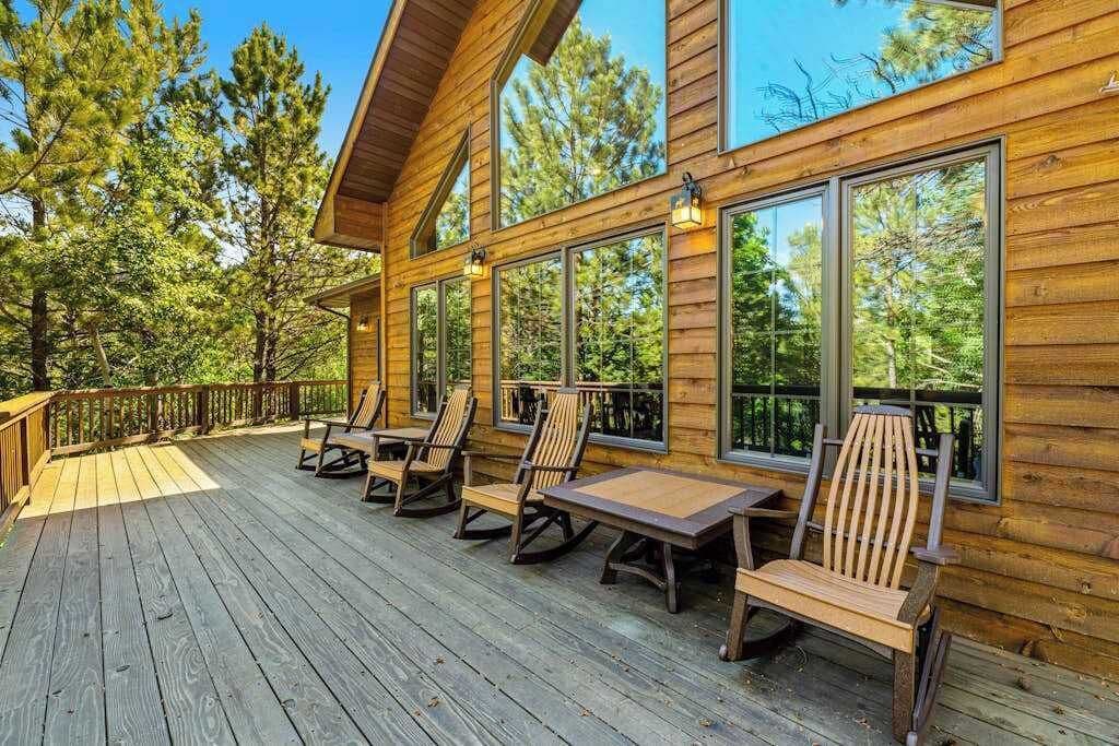 A wooden deck with outdoor seating and large windows.