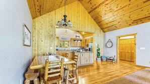 A spacious kitchen with wooden cabinets, a dining area with a wooden table and chairs, and a wooden ceiling. - Lazy Bear Lodge - Rustic Lodge • Hot Tub & Wrap Deck (Sturgis)