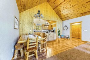 A spacious kitchen with wooden cabinets, a dining area with a wooden table and chairs, and a wooden ceiling. - Lazy Bear Lodge - Rustic Lodge • Hot Tub & Wrap Deck (Sturgis)