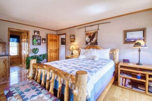 Ein Schlafzimmer mit einem Holzbettgestell, einem Nachttisch mit Lampe, einem Bücherregal und einer Tür zu einem anderen Raum.