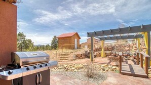 Eine Terrasse mit Grill, Gartenmöbeln und einer Pergola.