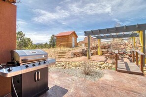 Eine Terrasse mit Grill, Gartenmöbeln und einer Pergola.