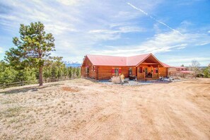 A wooden cabin with a red roof, a porch, and a dirt driveway. - Mills Ranch - Hot Tub Cabin • Pikes Peak Views (Woodland Park)