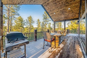An outdoor deck with a grill, chairs, and a table. - Pillar Peak Perch - Luxury Lodge • Hot Tub & Big Views (Sturgis)