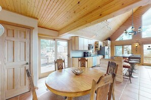 A wooden interior with a dining table, chairs, a kitchen area, and a bar with stools. - Peak View Vista - Secluded Home • Mtn Views on 5 Acres (Florissant)
