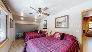 Ein Schlafzimmer mit zwei Betten, einem Deckenventilator und gerahmten Bildern an der Wand.