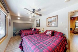 Ein Schlafzimmer mit zwei Betten, einem Deckenventilator und gerahmten Bildern an der Wand.
