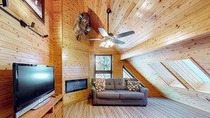 Ein gemütliches Zimmer mit Fernseher, Sofa und Deckenventilator.