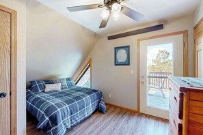 A bedroom with a bed, a ceiling fan, a door leading to a balcony, and a small table. - Buffalo Lodge - Ski-Area Cabin • Hot Tub & Views (Lead)