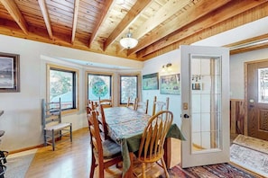 A dining area with a wooden ceiling, large windows, and a door with a glass panel. - Buffalo Lodge - Ski-Area Cabin • Hot Tub & Views (Lead)