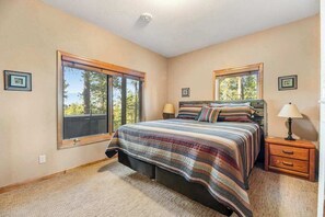 Une chambre à coucher avec un lit, deux tables de chevet, une fenêtre et une porte.