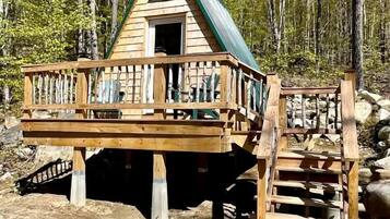 A wooden cabin with a balcony and a staircase leading to a deck.
