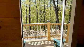 A wooden deck with a bench and a door leading to an outdoor area with trees.