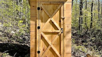 A wooden shed with a cross-braced door in a forested area.