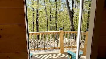 Una terraza de madera con un banco y una puerta que da a un espacio al aire libre con árboles.