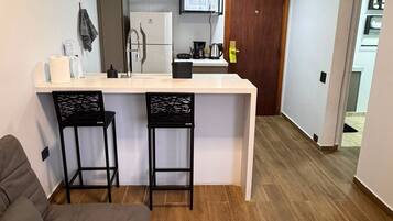 Um espaço compacto com cozinha compacta, sofá e porta que dá para outro quarto.