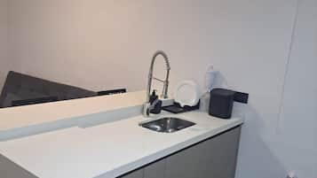 Uma cozinha moderna com pia embutida, armários cinza e bancada branca.
