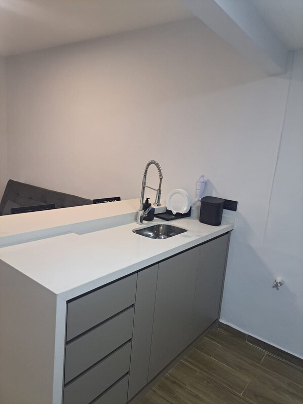 A modern kitchen with a built-in sink, grey cabinets, and a white countertop.