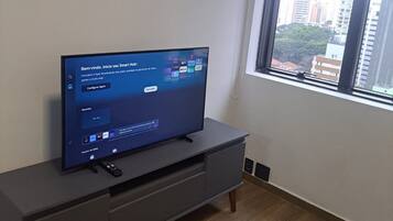 Uma televisão sobre um armário cinzento numa divisão com uma janela.