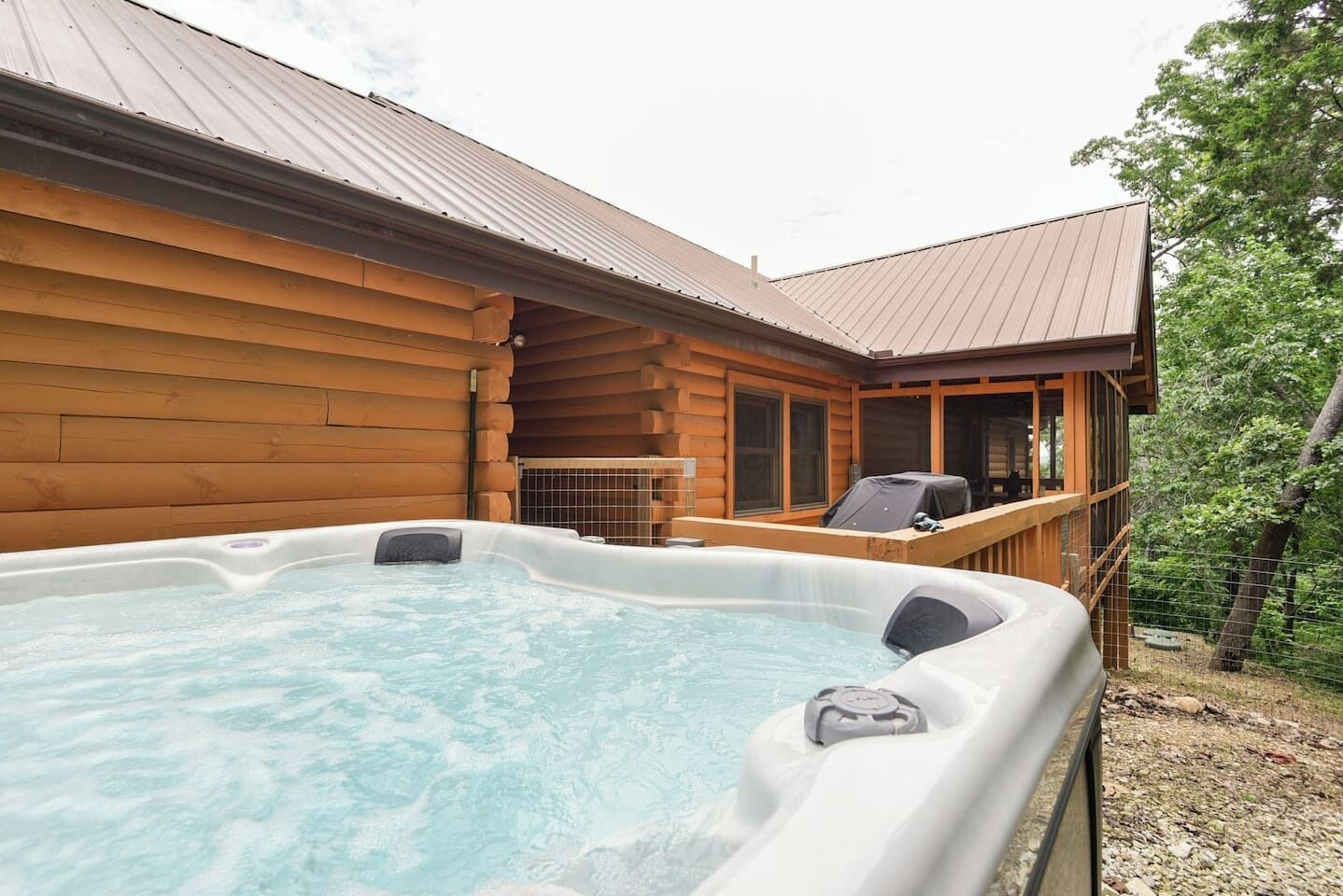 A wooden cabin with a hot tub and outdoor seating.