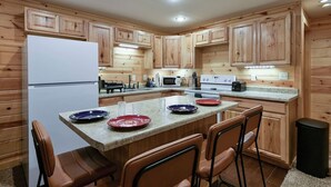 A kitchen with wooden cabinets, a white refrigerator, a microwave, a stove, and a granite countertop.