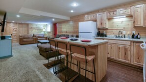 A compact kitchen with a central island, wooden cabinets, and a dining area with a sofa and chairs.