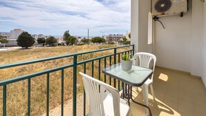 A balcony with a table and chairs, a Samsung air conditioner, and a view of a residential area. - Ref gio do Mar by Acasadascasas (Mafra)