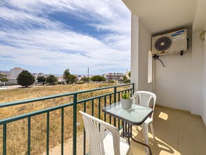 A balcony with a table and chairs, a Samsung air conditioner, and a view of a residential area. - Ref gio do Mar by Acasadascasas (Mafra)