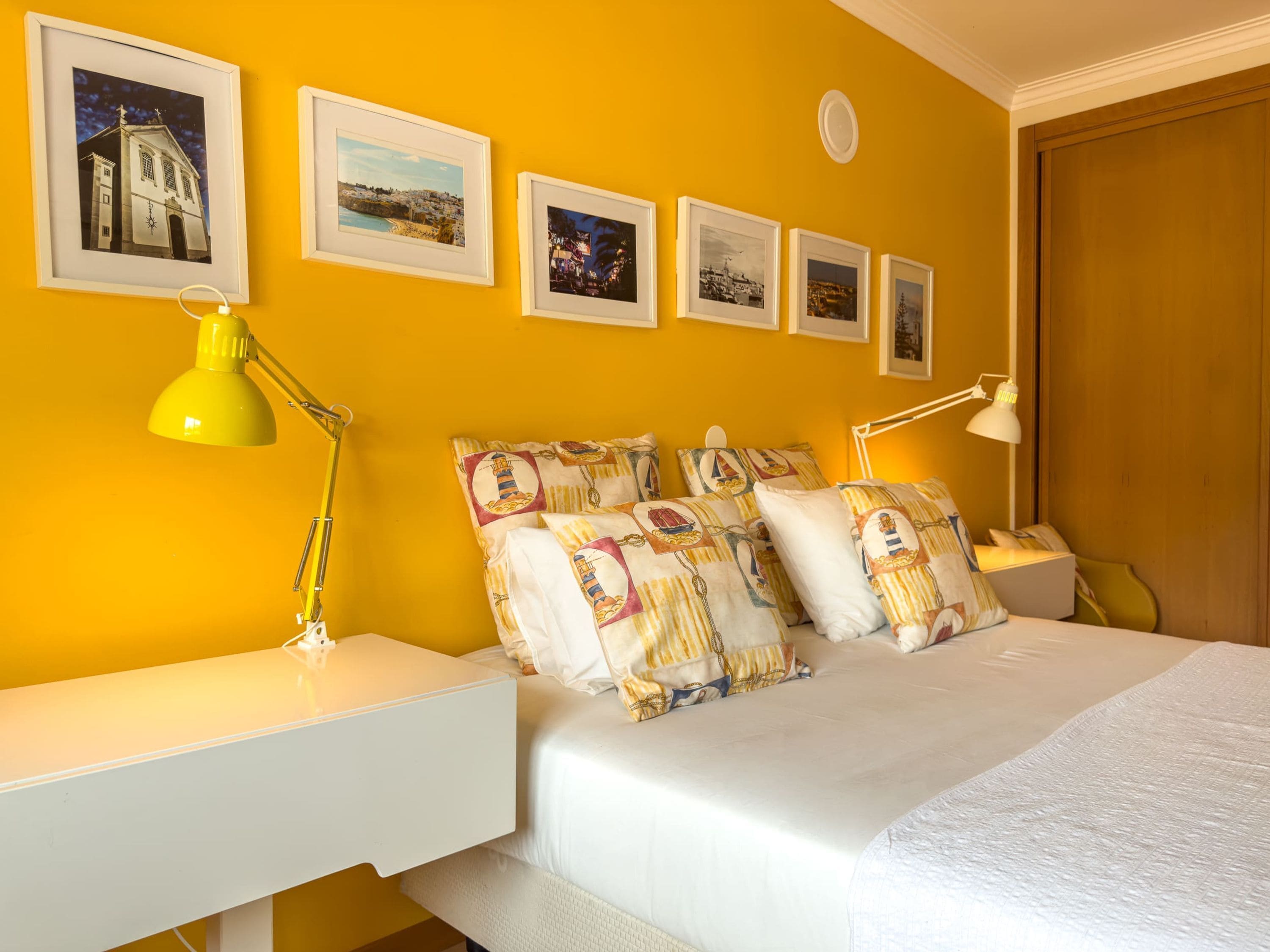 Ein Hotelzimmer mit einem Bett, zwei Nachttischen, einer Lampe und gerahmten Bildern an der Wand.