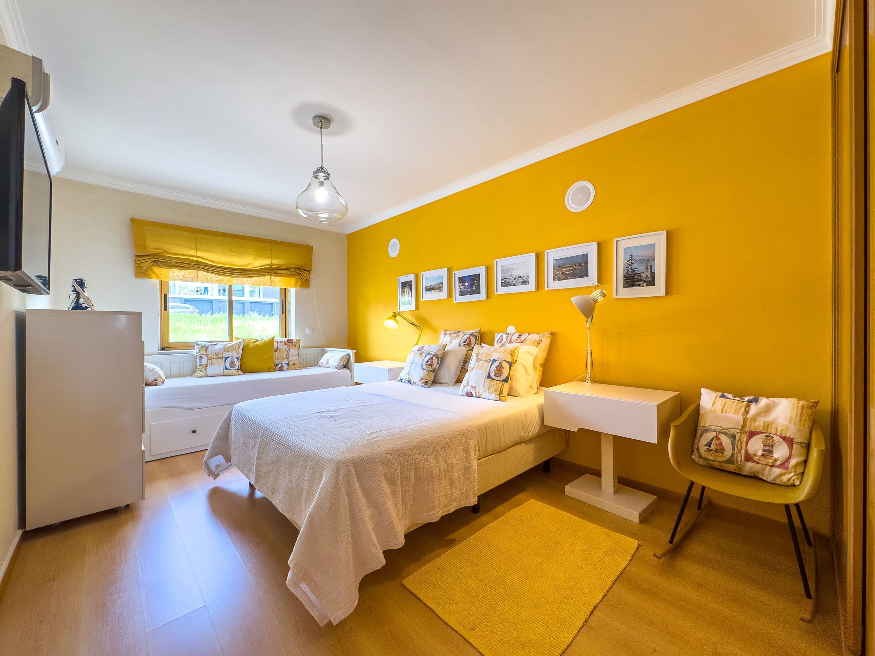 Un dormitorio con dos camas, una ventana con vistas, un televisor de pantalla plana y una pared de acento amarilla.