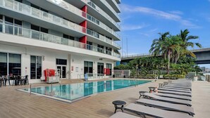 Um hotel com piscina, espreguiçadeiras e vista para palmeiras.