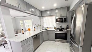 A modern kitchen with grey cabinets, a stainless steel refrigerator, and a built-in oven. - Spacious Townhome near Disney (Davenport)