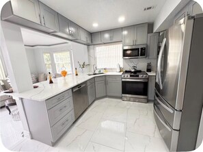A modern kitchen with grey cabinets, a stainless steel refrigerator, and a built-in oven. - Spacious Townhome near Disney (Davenport)