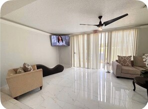 A spacious living room with a flat-screen TV, a ceiling fan, and a sofa. - Spacious Townhome near Disney (Davenport)