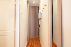 A narrow hallway with wooden flooring, a striped wall, and a door on the left. - GuestReady - Stay in the Heart of Lisbon (Lisbon)