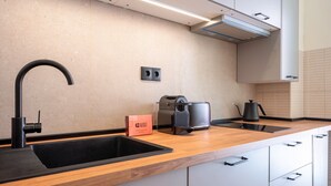 Una cocina moderna con un lavabo negro, una cafetera y un hervidor.