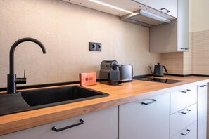 Eine moderne Küche mit einem schwarzen Spülbecken, einer Kaffeemaschine und einem Wasserkocher.