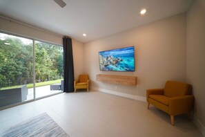 A modern living room with a large sliding glass door leading to a balcony, a painting on the wall, and two armchairs. - Royal View Retreat-1212 (Kissimmee)