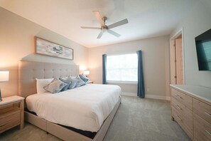 A bedroom with a bed, nightstands, a ceiling fan, a window with curtains, and a TV on a dresser. - Royal View Retreat-1212 (Kissimmee)