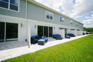 A modern building with a covered outdoor seating area and a well-maintained lawn. - Royal View Retreat-1212 (Kissimmee)