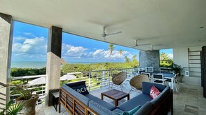 A balcony with a view of the ocean, furnished with a sofa, chairs, and a table. - Amazing beachfront Luxury Villa with chef and housekeeping service at Sisal, Yuc (Sisal)