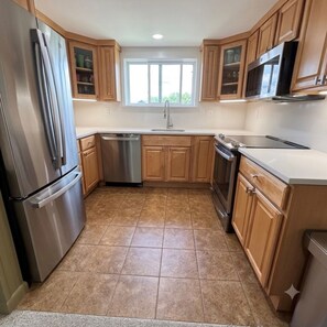 A kitchen with wooden cabinets, stainless steel appliances, and a window above the sink. - Family friendly condo at Smugglers Notch Resort (Cambridge)