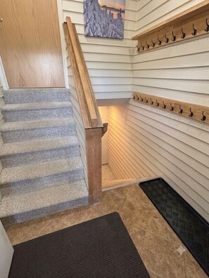 A staircase with a wooden handrail, a wall-mounted coat rack, and a door. - Family friendly condo at Smugglers Notch Resort (Cambridge)